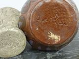 a brown vase and a stone on a table