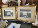 two framed pictures that are on a table in a room