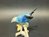 figurine of a blue bird sitting on a branch on a gray background