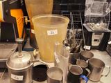 a counter with a blender, a blender, cups, and other items on it
