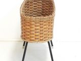 a wicker basket on a metal stand on a white floor
