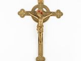 a gold crucifix with a red stone in the center
