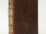 an old book with a brown cover sitting on top of a white surface