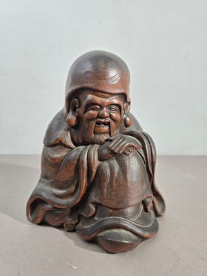 une vieille statue en bois représentant un homme assis sur une table
