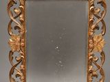 an ornate gold framed mirror with leaves and scrolls on a gray background