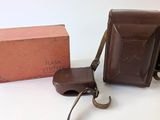 une mallette marron et un sac marron posés sur une table blanche