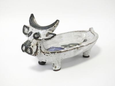 une vache en céramique posée sur une surface blanche