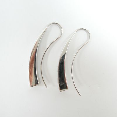 une paire de boucles d'oreilles en argent et en bois posées sur une surface blanche
