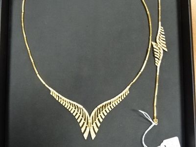 un collier en or orné d'une flèche, présenté dans un coffret noir