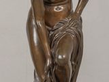 bronze statue of a man sitting on a rock with his hands on his knees