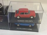 three miniature cars in a display case on a table