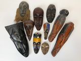 Plusieurs masques africains sont disposés en cercle sur une surface blanche
