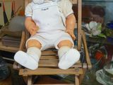 une poupée assise sur une chaise dans une vitrine