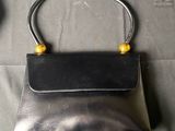black leather purse with gold accents on top of a bed