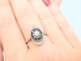 woman ' s hand holding a blue and white diamond ring