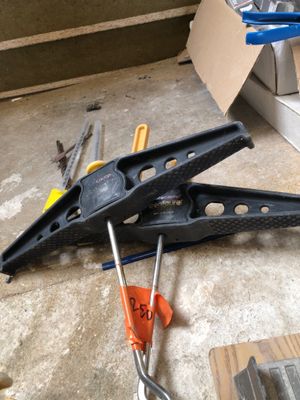a clamp that is laying on the floor next to some tools