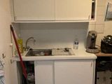 une petite cuisine avec des placards blancs et une serpillière rouge à l'intérieur