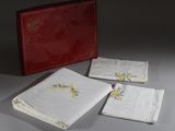 trois serviettes blanches ornées de fleurs bleues et jaunes se trouvent à côté d'une boîte rouge