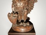 statue of an owl holding a cup on a wooden base