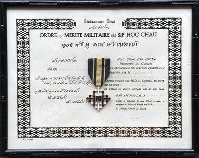 photo encadrée d'une médaille et d'un certificat, exposée dans un cadre noir