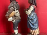 two figurines of a man and a woman standing on a red surface