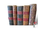 several old books are stacked on top of each other on a white surface
