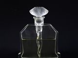 a clear glass perfume bottle sitting on top of a black surface