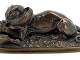 bronze statue of a dog laying down on the ground with a hat on it ' s head