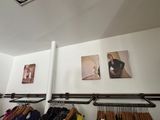 a rack of clothes in a clothing store with pictures on the wall