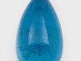 a close up of a blue glass tear shaped object on a white surface