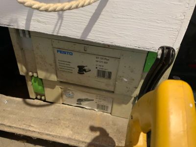 une boîte blanche surmontée d'une corde, à côté d'un poteau jaune