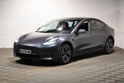 the tesla model 3 is parked in a garage with a checkered floor
