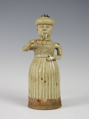une vieille figurine en céramique représentant une femme en robe et avec un chapeau
