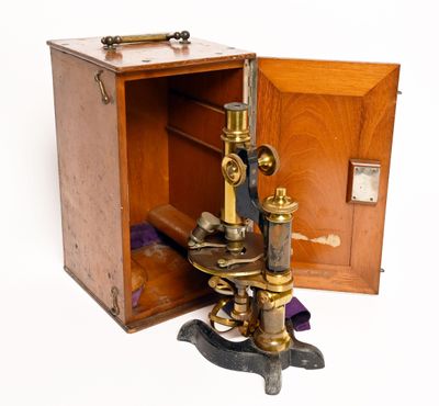 un vieux microscope en laiton rangé dans une boîte en bois