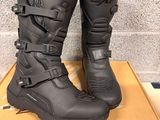 black motorcycle boots with buckles on top of a cardboard box