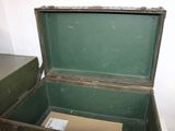 a green suitcase sitting on the floor next to a brown box