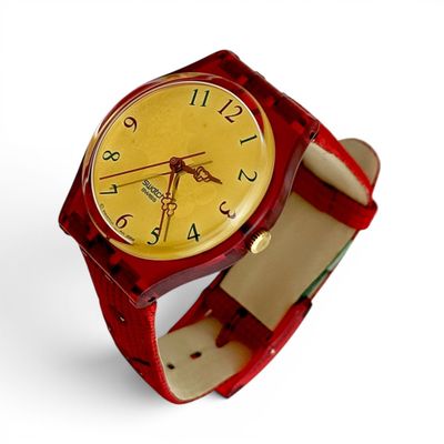 une montre-bracelet rouge avec un cadran jaune sur fond blanc