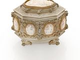 an antique silver box with a white and gold design on the lid