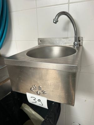 a stainless steel sink in the corner of a bathroom
