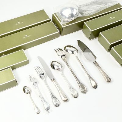beaucoup d'argenterie dans une boîte verte posée sur une table blanche