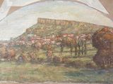 une peinture accrochée au mur d'un immeuble, avec une montagne en arrière-plan