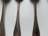 four spoons are lined up on a white surface