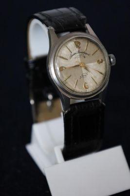 an old watch on a stand on a black background