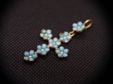 a gold cross pendant with turquoise stones on a black background