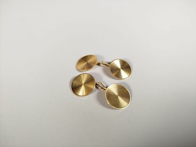 a pair of gold cufflinks on a white surface