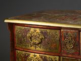 a red and gold chest of drawers on a black background