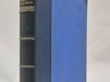 un vieux livre à la couverture bleue posé sur une table blanche