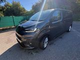 une camionnette noire garée sur un parking, avec des arbres en arrière-plan
