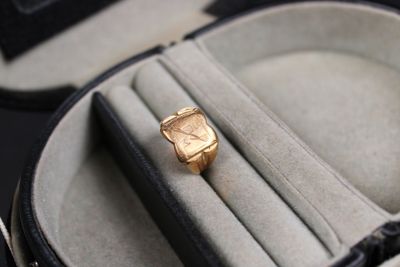 a gold watch sitting in a case with a ring in it