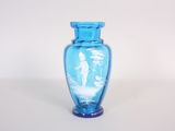 un vase en verre bleu sur lequel est représenté un homme et une femme